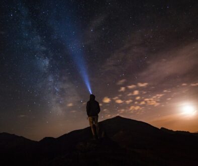 man standing at mountain peak under starry night sky