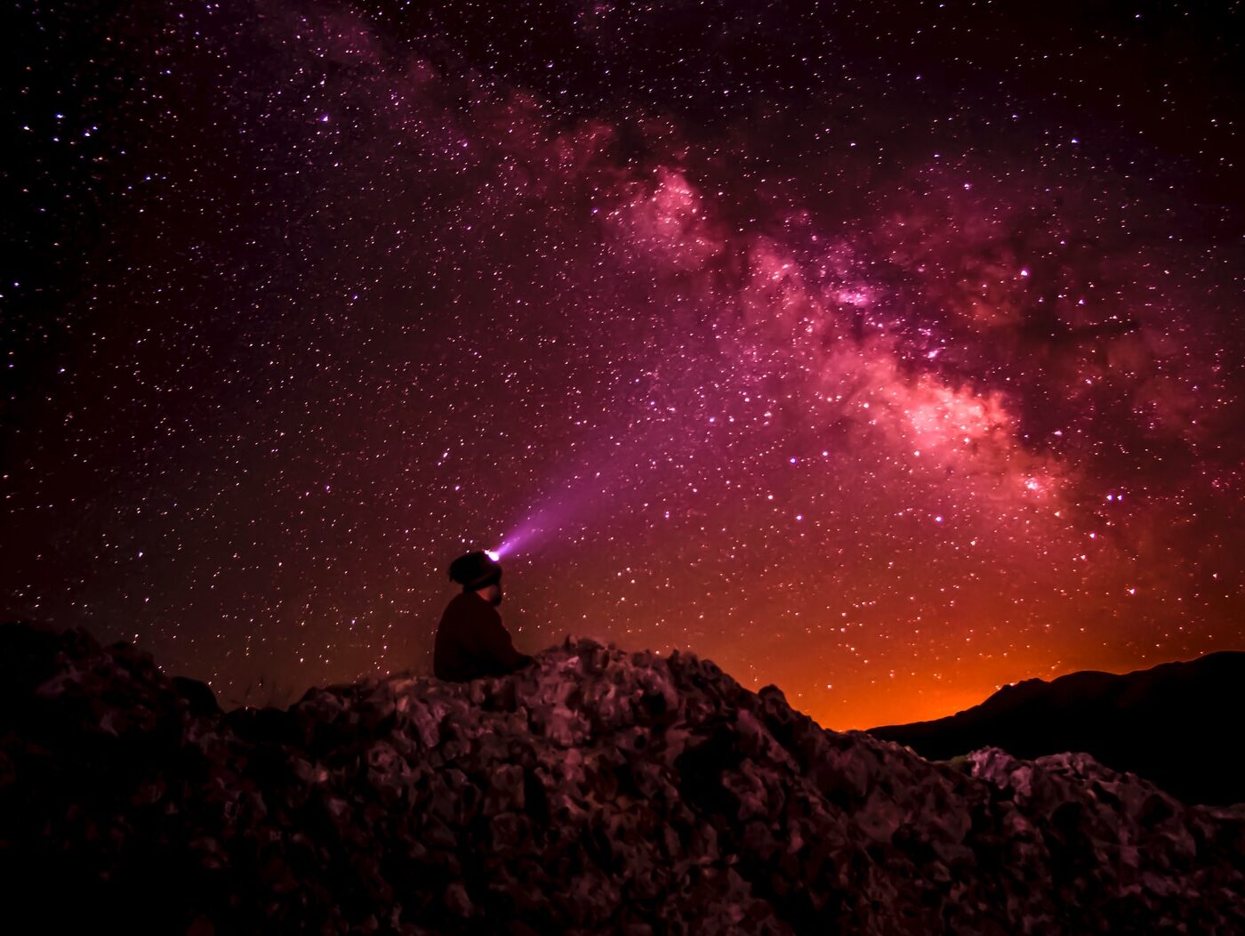silhouette photo of person holding flashlight under milk way