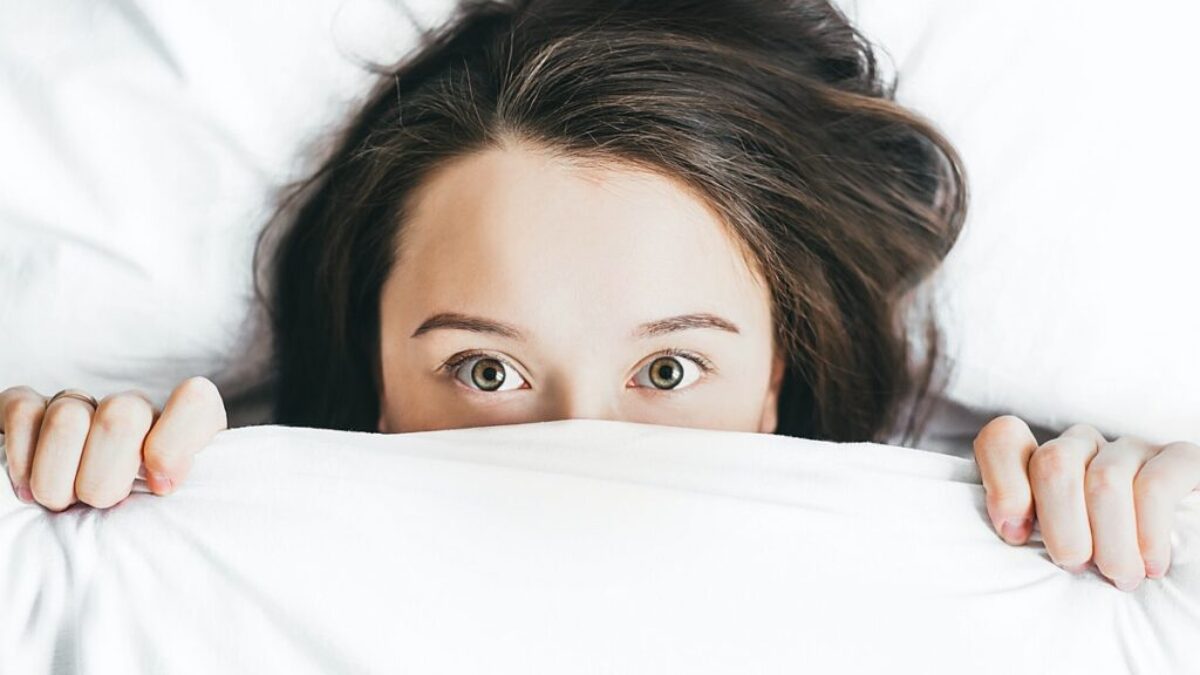 woman covering her face with blanket