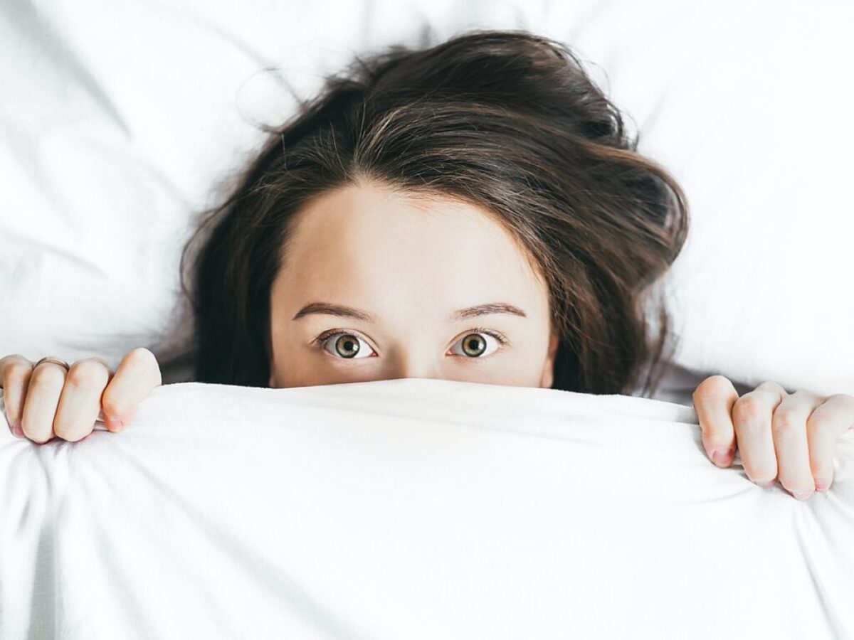 woman covering her face with blanket