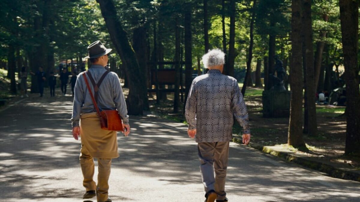 man in blue and white plaid dress shirt and brown pants walking on gray concrete road