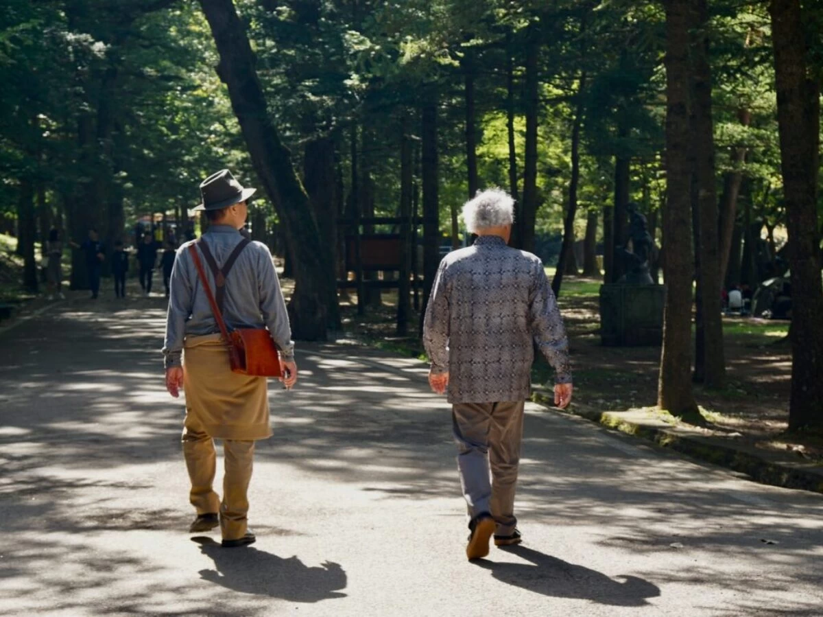 man in blue and white plaid dress shirt and brown pants walking on gray concrete road
