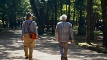 man in blue and white plaid dress shirt and brown pants walking on gray concrete road