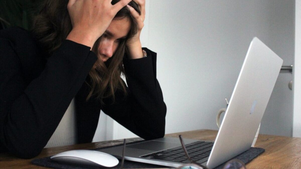 woman in black long sleeve shirt covering her face with her hands
