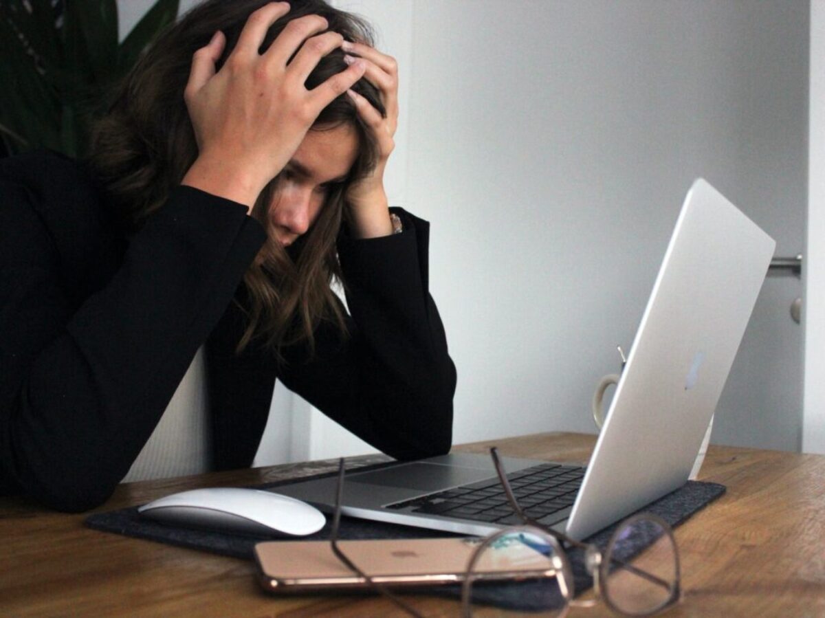 woman in black long sleeve shirt covering her face with her hands