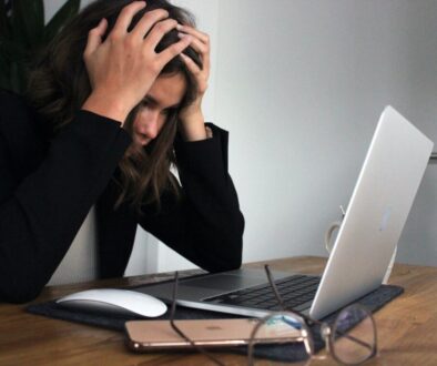 woman in black long sleeve shirt covering her face with her hands