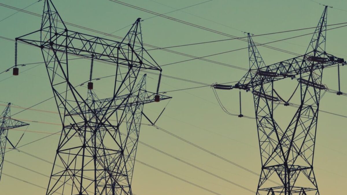 black transmission towers under green sky