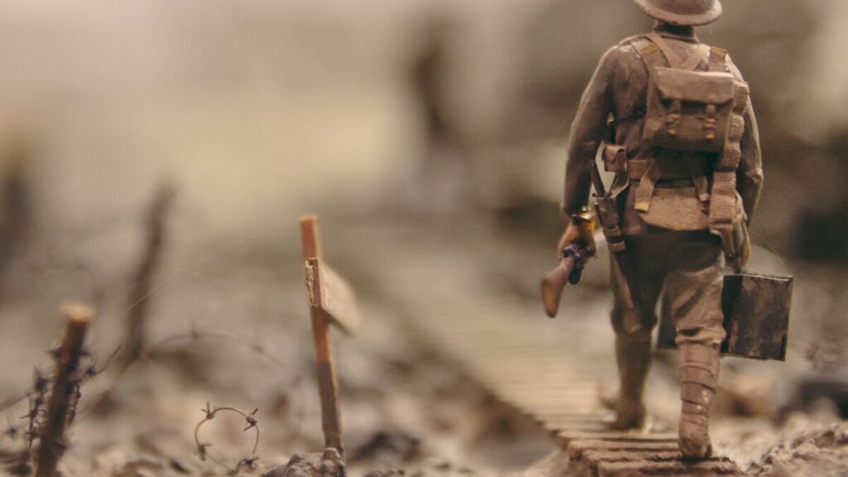 soldier walking on wooden pathway surrounded with barbwire selective focus photography