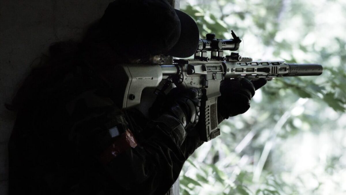man in black jacket holding black rifle