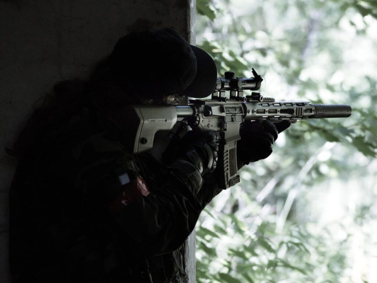 man in black jacket holding black rifle