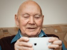 man in blue and black pinstripe dress shirt holding white smartphone