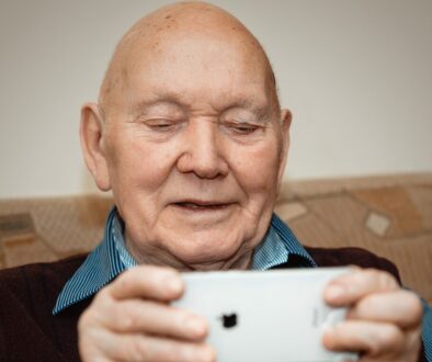 man in blue and black pinstripe dress shirt holding white smartphone