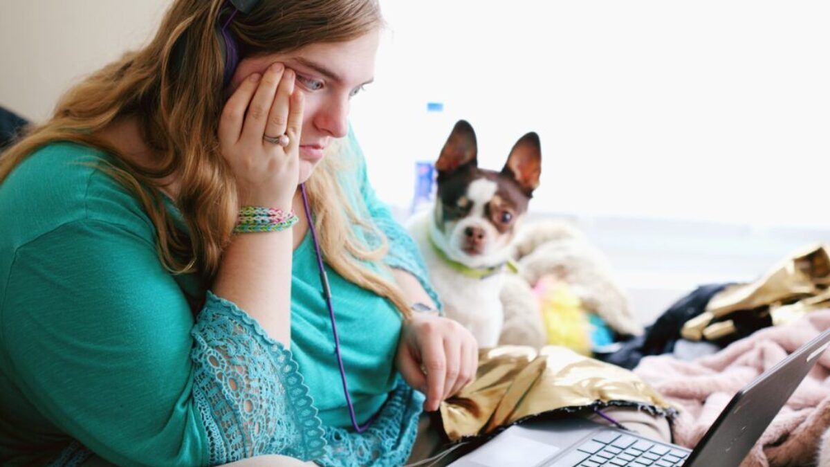 woman in teal long sleeve shirt holding black laptop computer