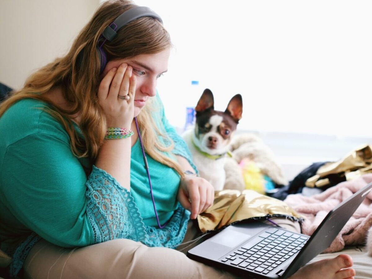 woman in teal long sleeve shirt holding black laptop computer