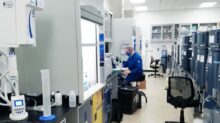 man in blue scrub suit standing near white and black office rolling chair