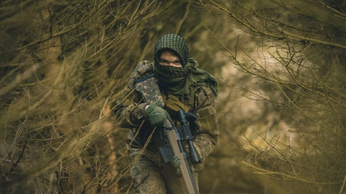 person in black and green camouflage jacket holding black rifle