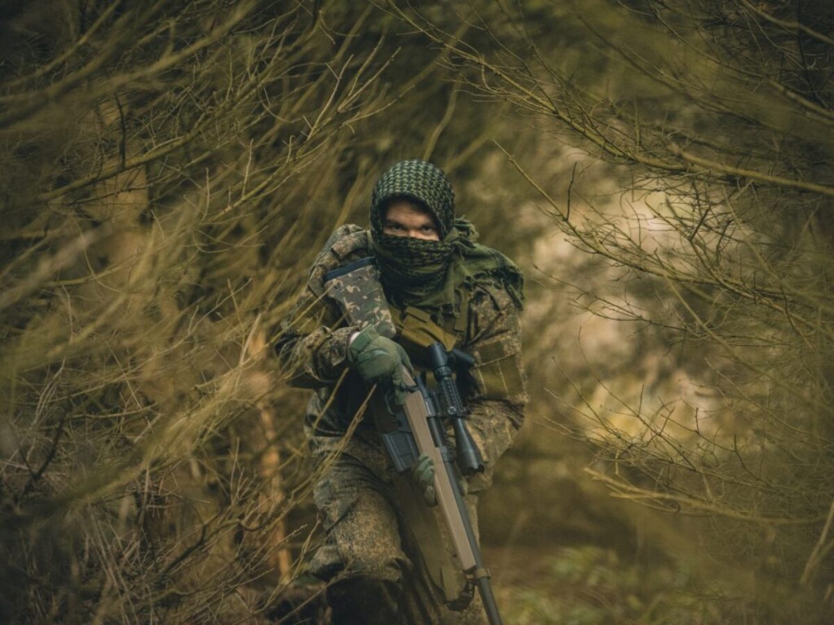 person in black and green camouflage jacket holding black rifle