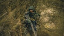 person in black and green camouflage jacket holding black rifle