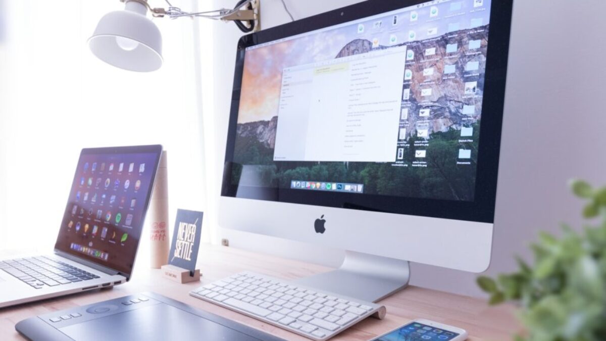 silver iMac near iPhone on brown wooden table