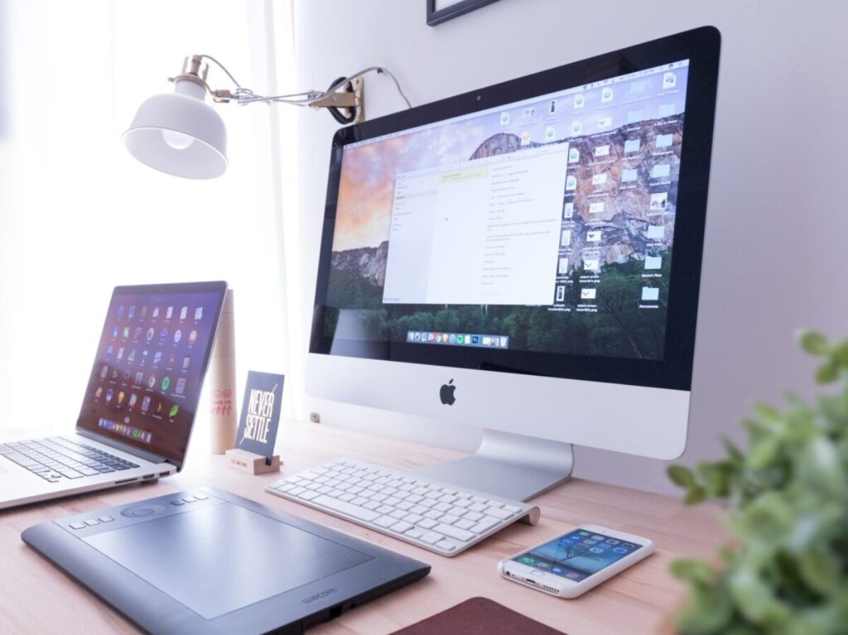 silver iMac near iPhone on brown wooden table