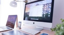 silver iMac near iPhone on brown wooden table