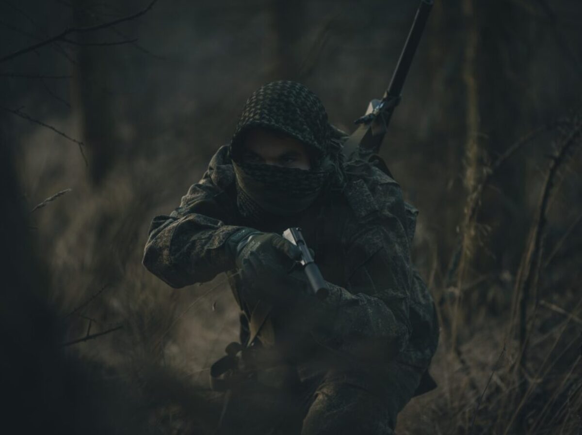 person in black and white hoodie holding rifle