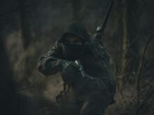 person in black and white hoodie holding rifle