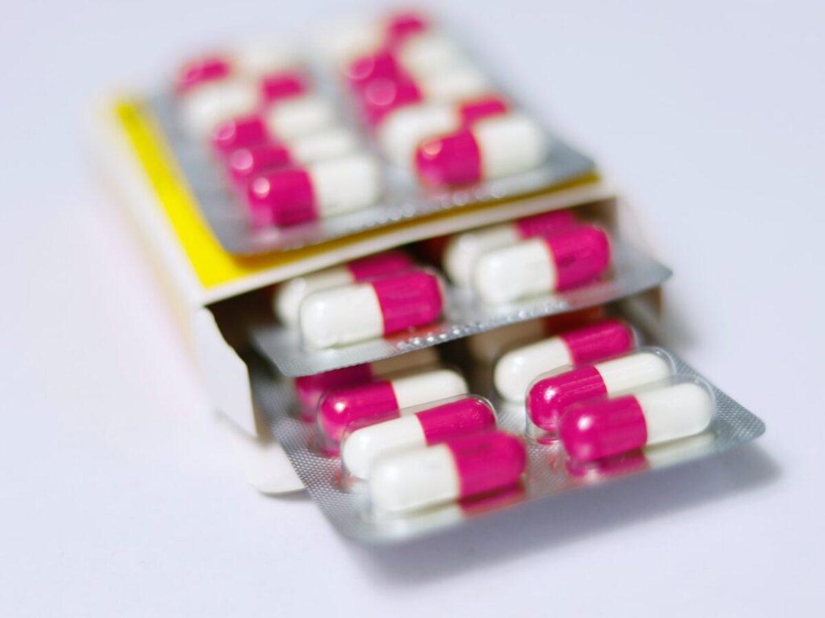 white and red medication pill on yellow box
