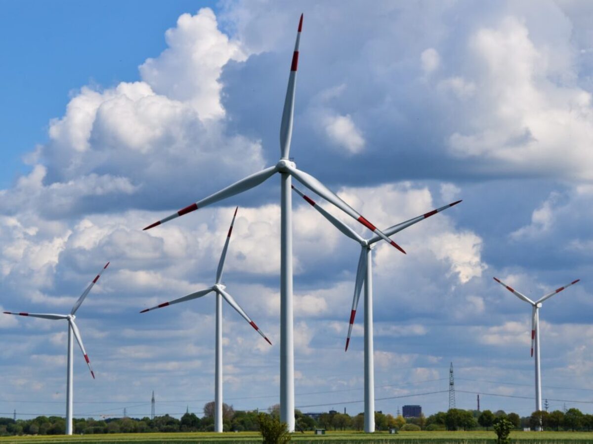 white wind turbines on green grass field under blue and white cloudy sky during daytime
