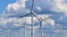 white wind turbines on green grass field under blue and white cloudy sky during daytime