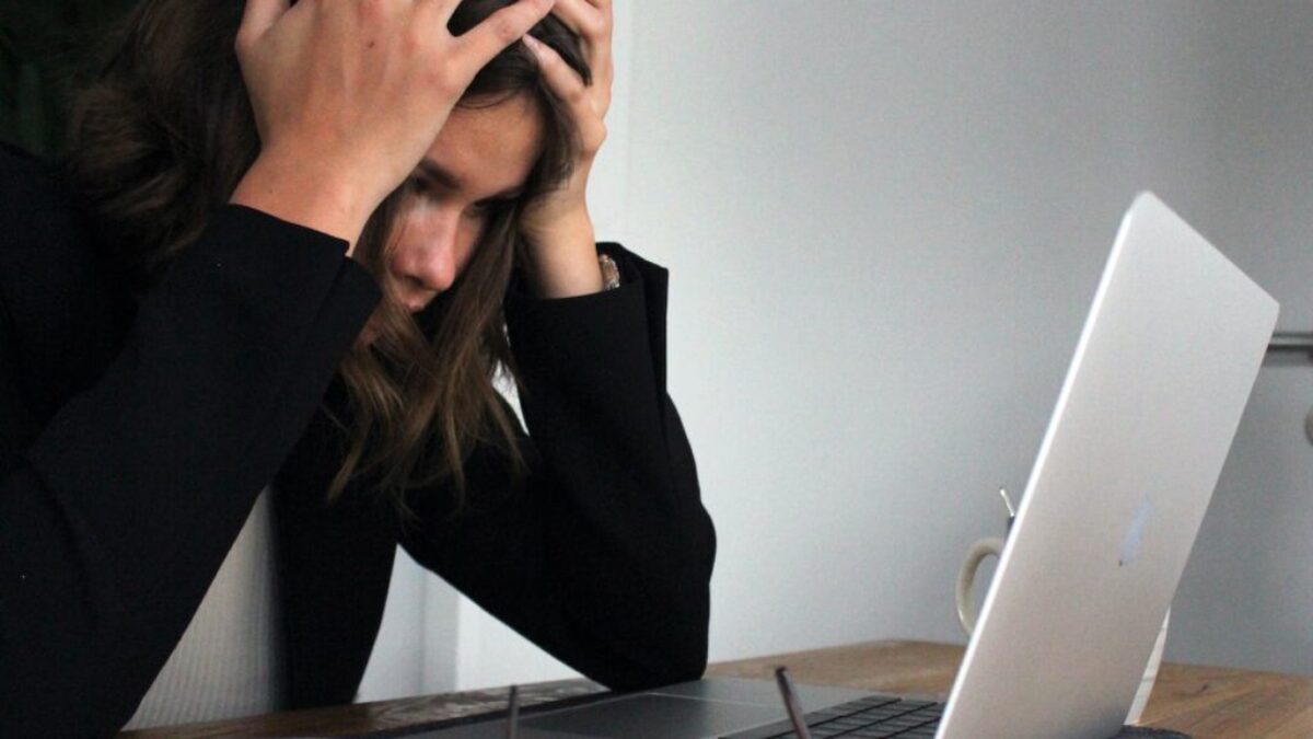 woman in black long sleeve shirt covering her face with her hands