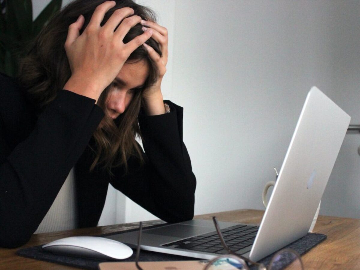 woman in black long sleeve shirt covering her face with her hands