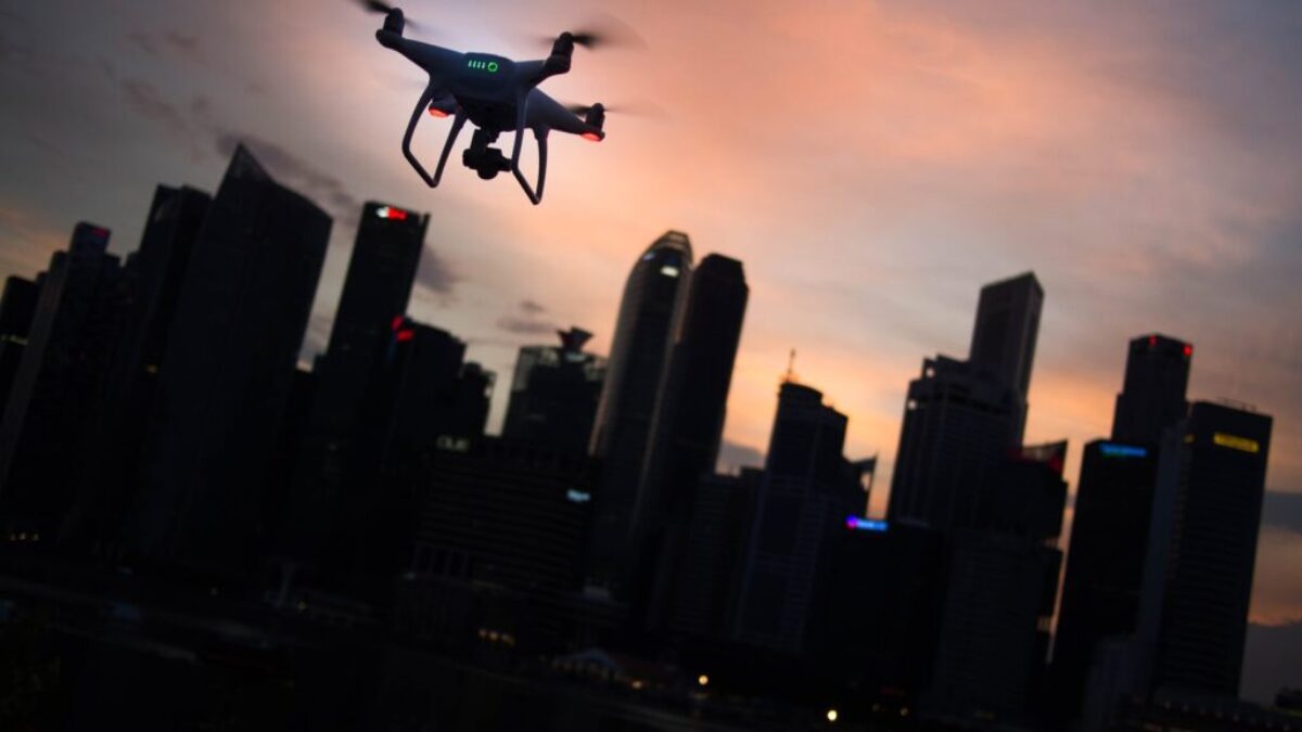 silhouette of quadcopter drone hovering near the city
