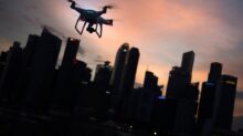 silhouette of quadcopter drone hovering near the city