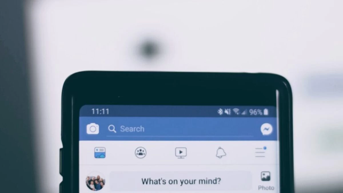 person holding smartphone using facebook account