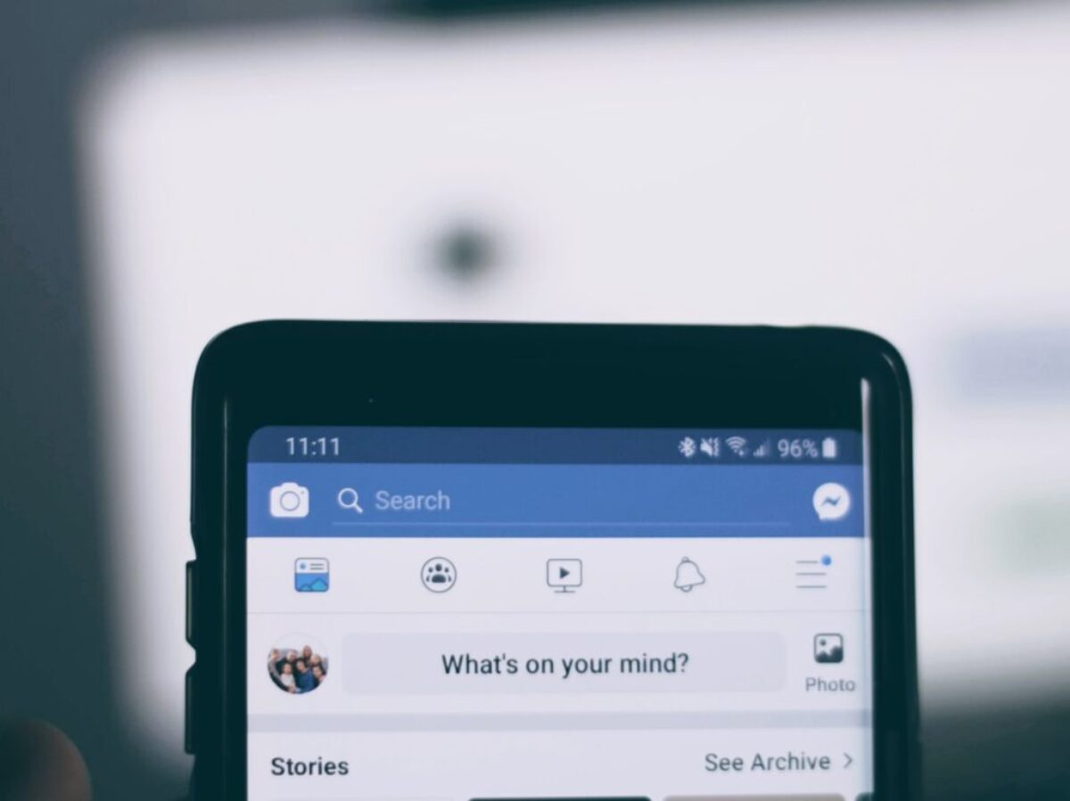 person holding smartphone using facebook account
