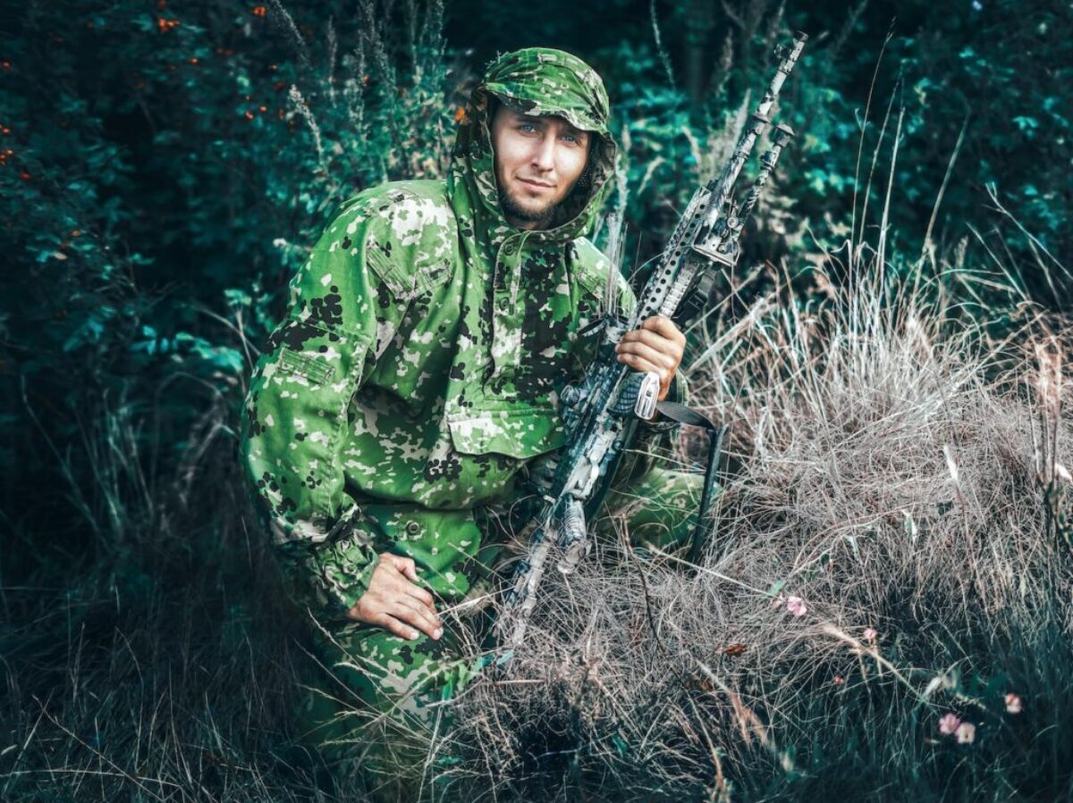 woman in green and black camouflage jacket holding black rifle
