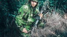 woman in green and black camouflage jacket holding black rifle