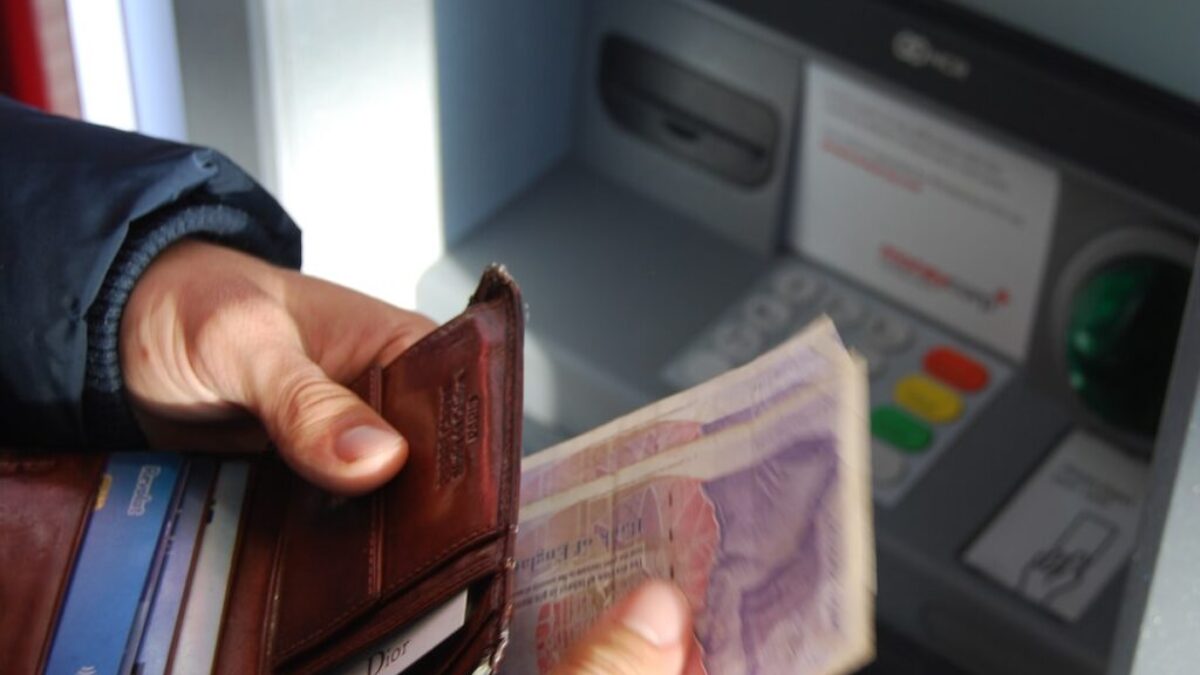 person holding brown leather wallet and banknotes