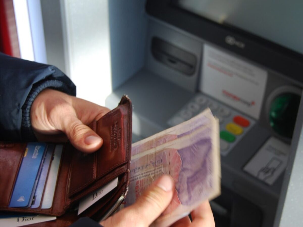 person holding brown leather wallet and banknotes