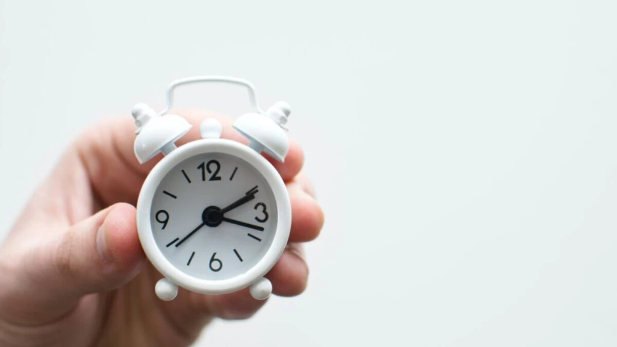 person holding white mini bell alarmclock
