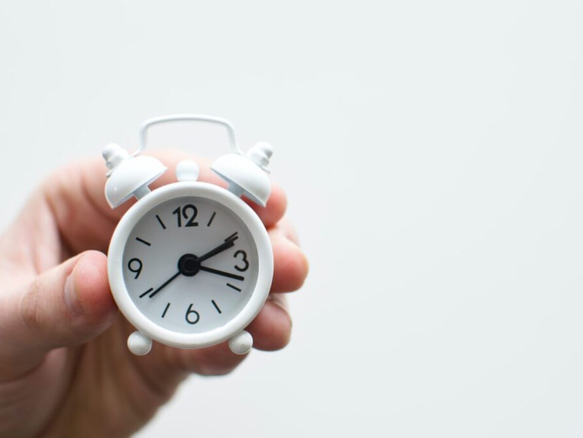 person holding white mini bell alarmclock
