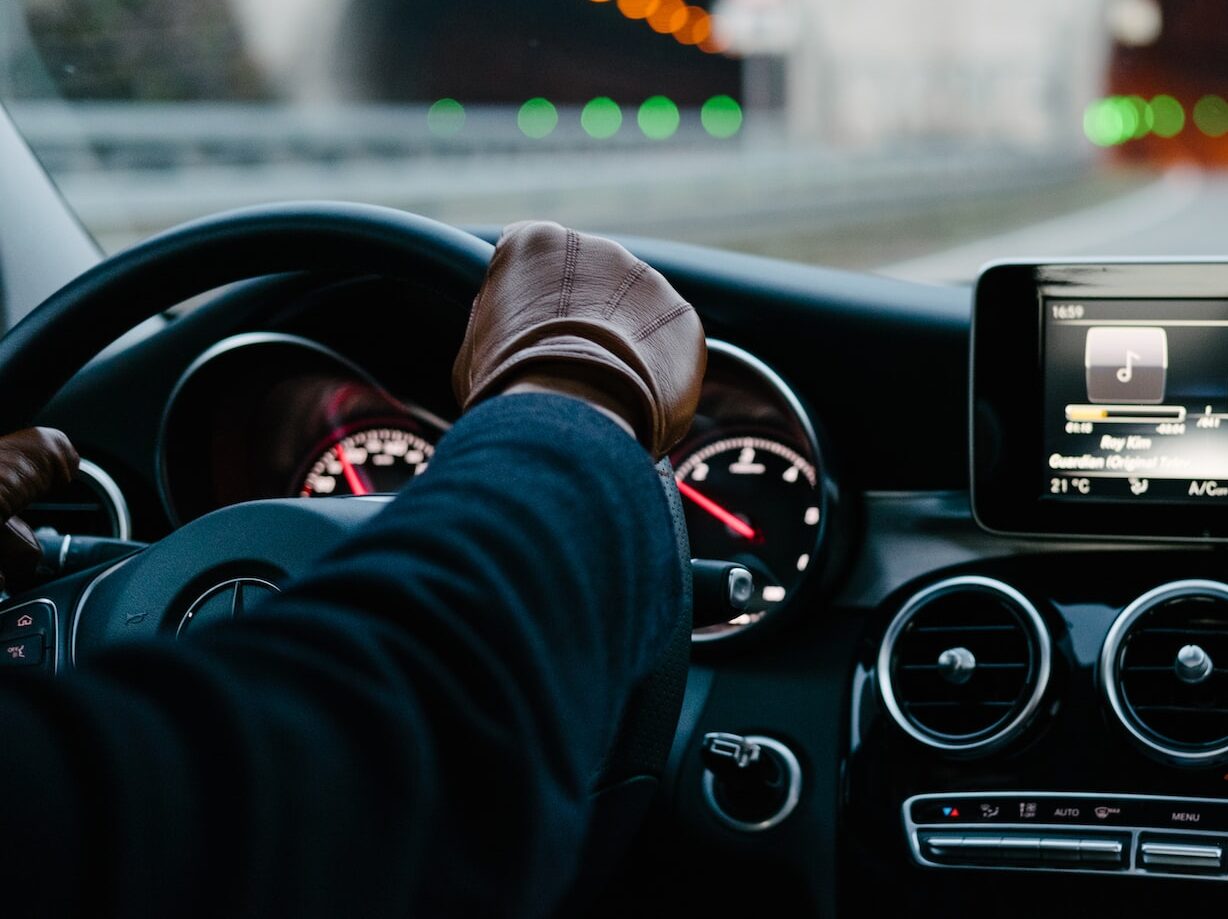 person inside vehicle holding steering wheel