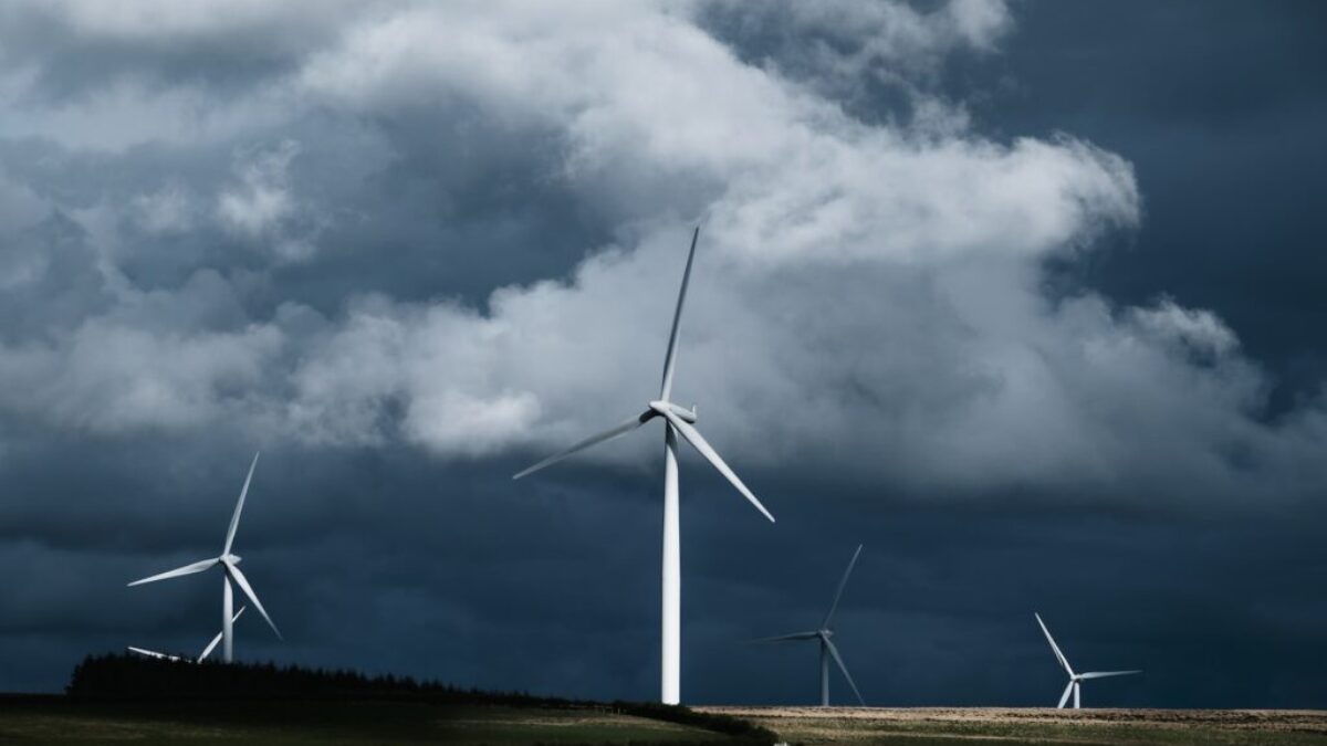 white wind turbines on green grass field under gray clouds