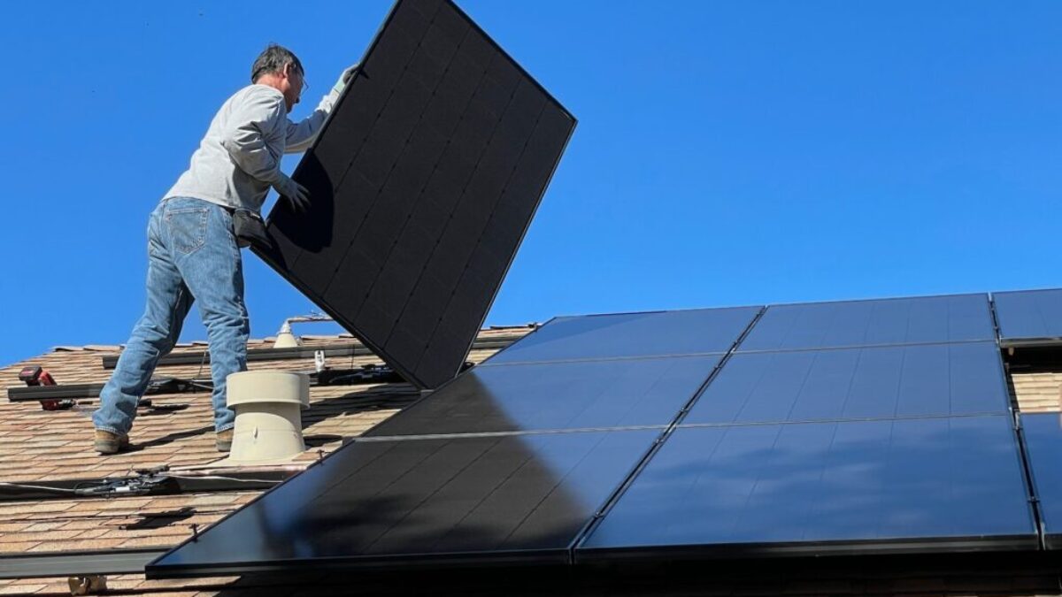 man in white dress shirt and blue denim jeans sitting on white and black solar panel