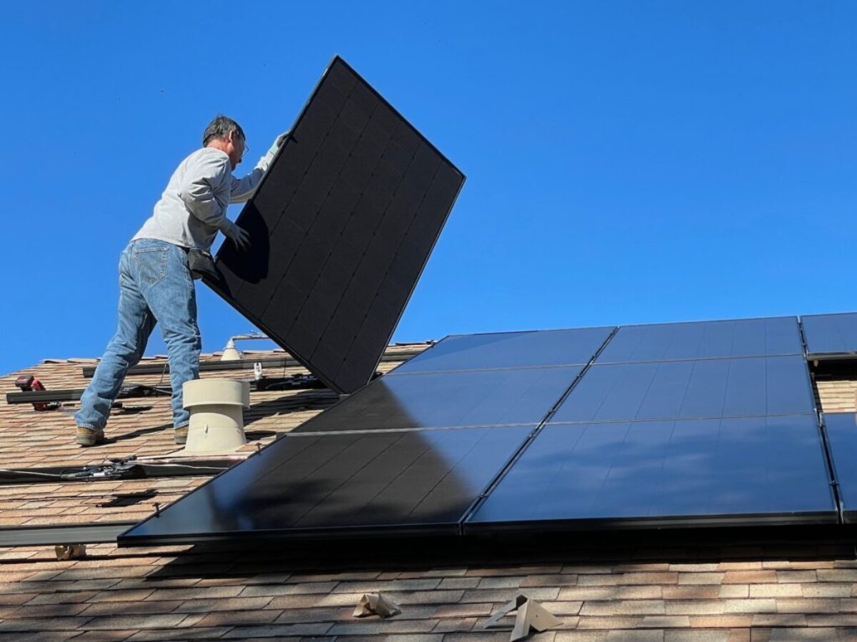 man in white dress shirt and blue denim jeans sitting on white and black solar panel