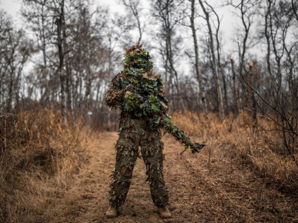 man in green and black camouflage jacket standing on brown grass field during daytime