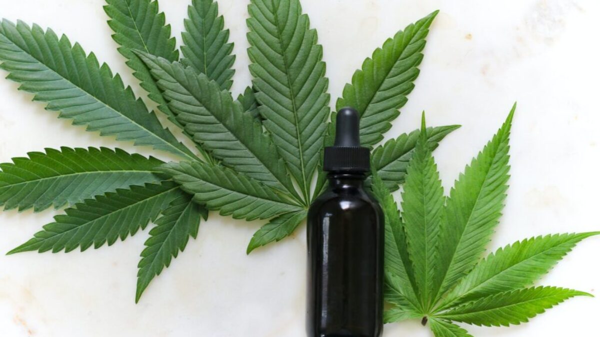 green cannabis leaves and black glass drops bottle