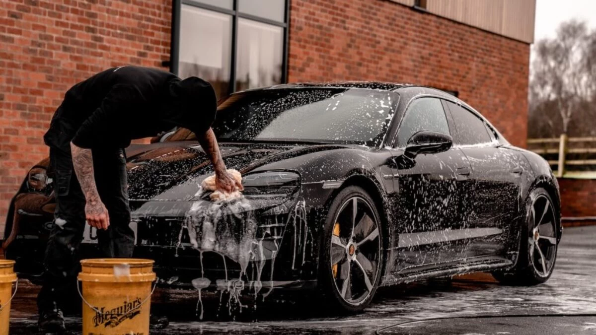 man in black t-shirt and black pants doing water splash on black coupe during daytime