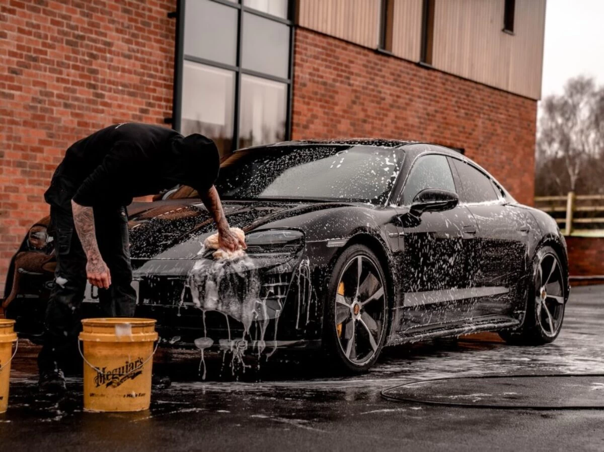 man in black t-shirt and black pants doing water splash on black coupe during daytime